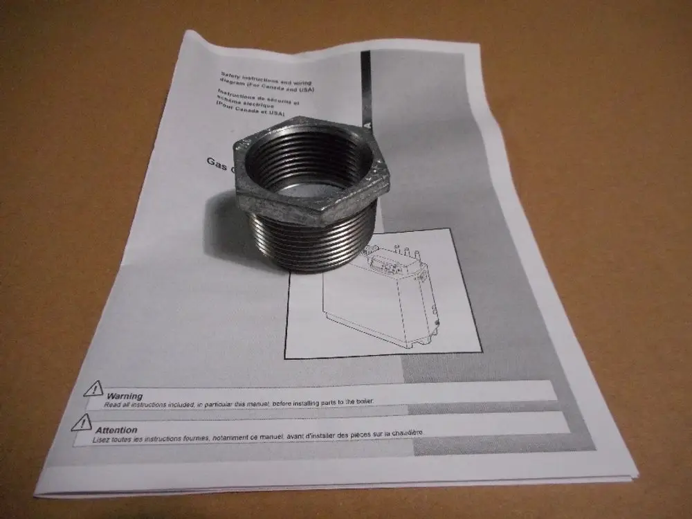 Muffe aus Metall, die auf einer Anleitung für Remeha-Produkte liegt. Die Anleitung enthält Warnhinweise und technische Informationen.